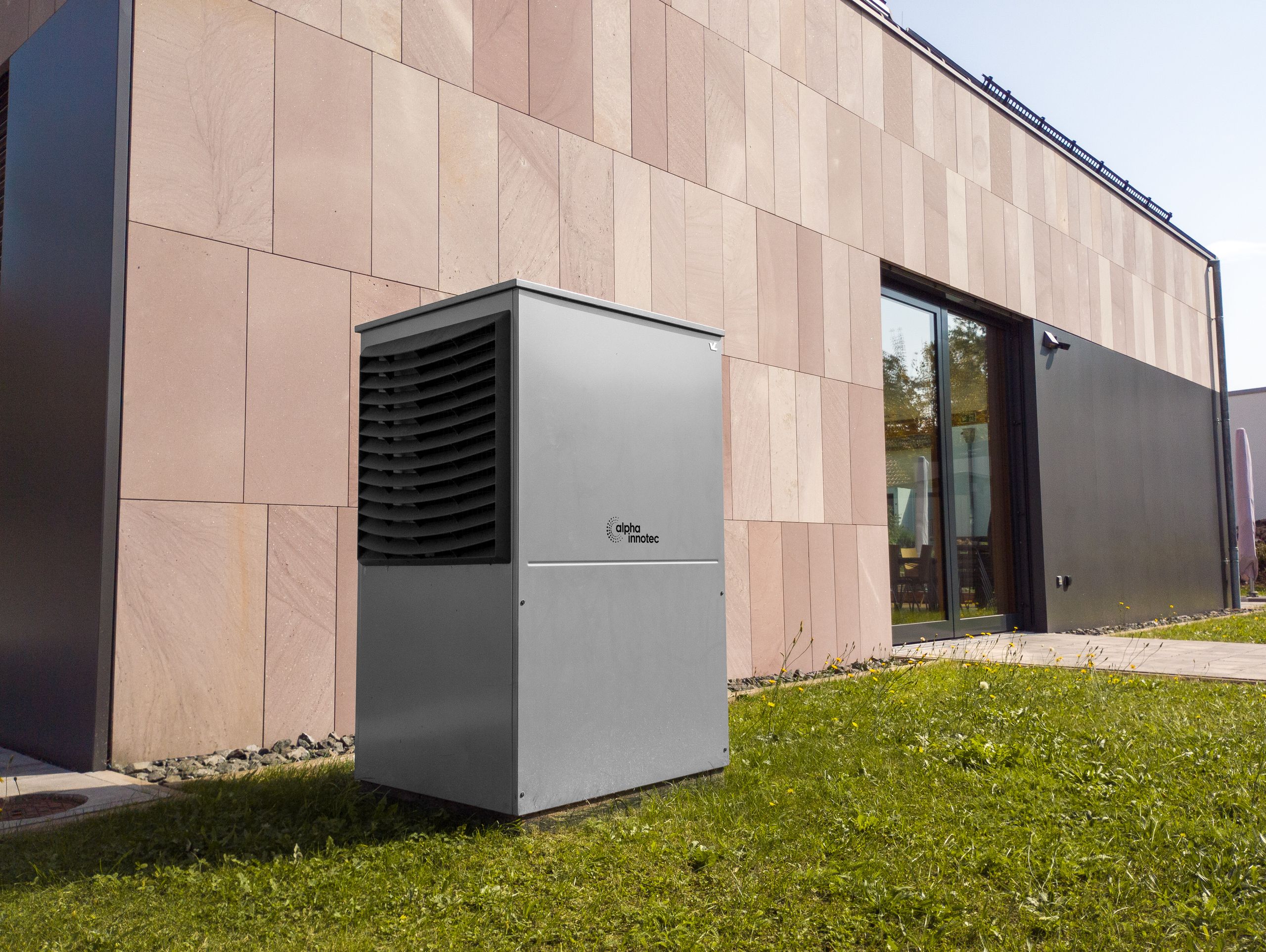 Does the Volvo EX30 Have a Heat Pump? A modern heat pump unit installed outdoors next to a contemporary building, showcasing renewable energy technology.