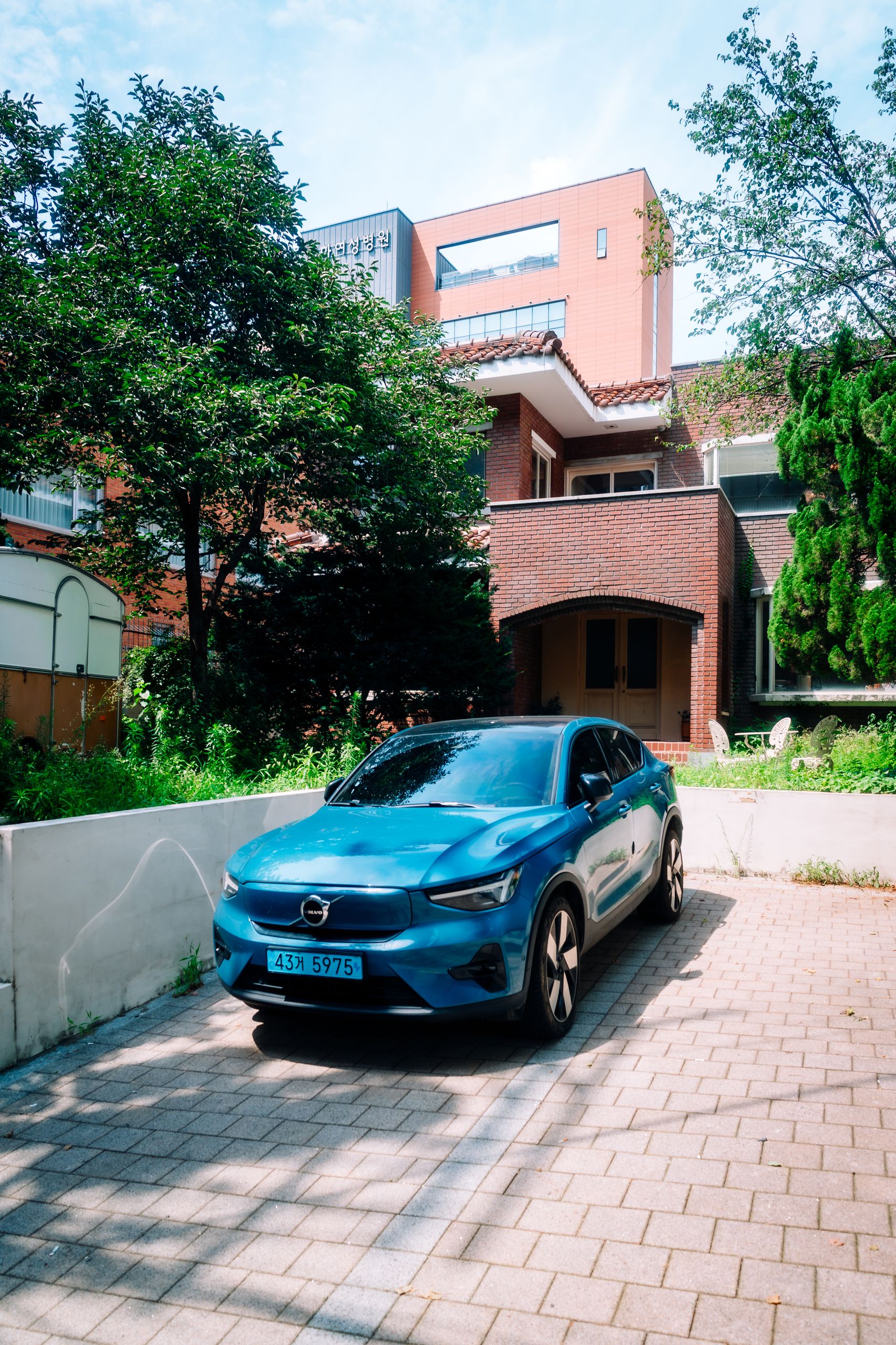 A sleek blue electric car parked in a residential driveway in Seoul, South Korea.