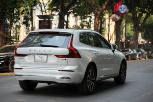 A white Volvo XC60 parked on a tree-lined street in a city setting.