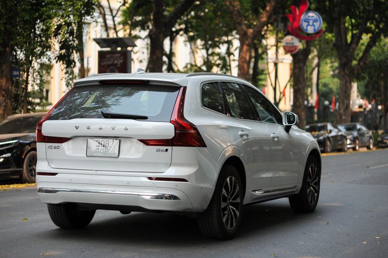 Where Is the Volvo XC60 Made? A white Volvo XC60 parked on a tree-lined street in a city setting.