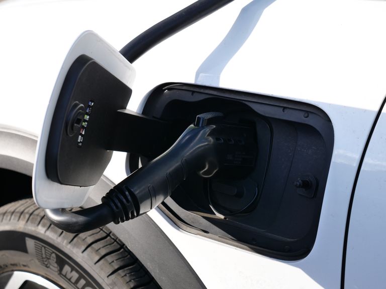 How to Charge Volvo XC40 Recharge? Close-up view of an electric vehicle charging with a focus on the connector and charging port.