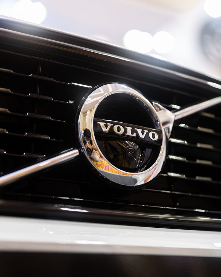 Detailed shot of Volvo emblem reflecting surroundings on a car grille, highlighting its classic design.