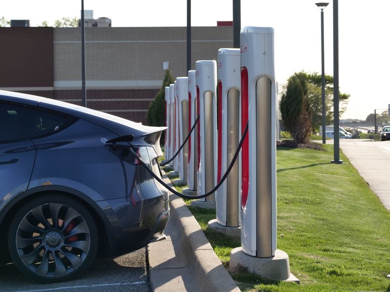 Electric car plugged into a row of charging stations, showcasing modern EV infrastructure.