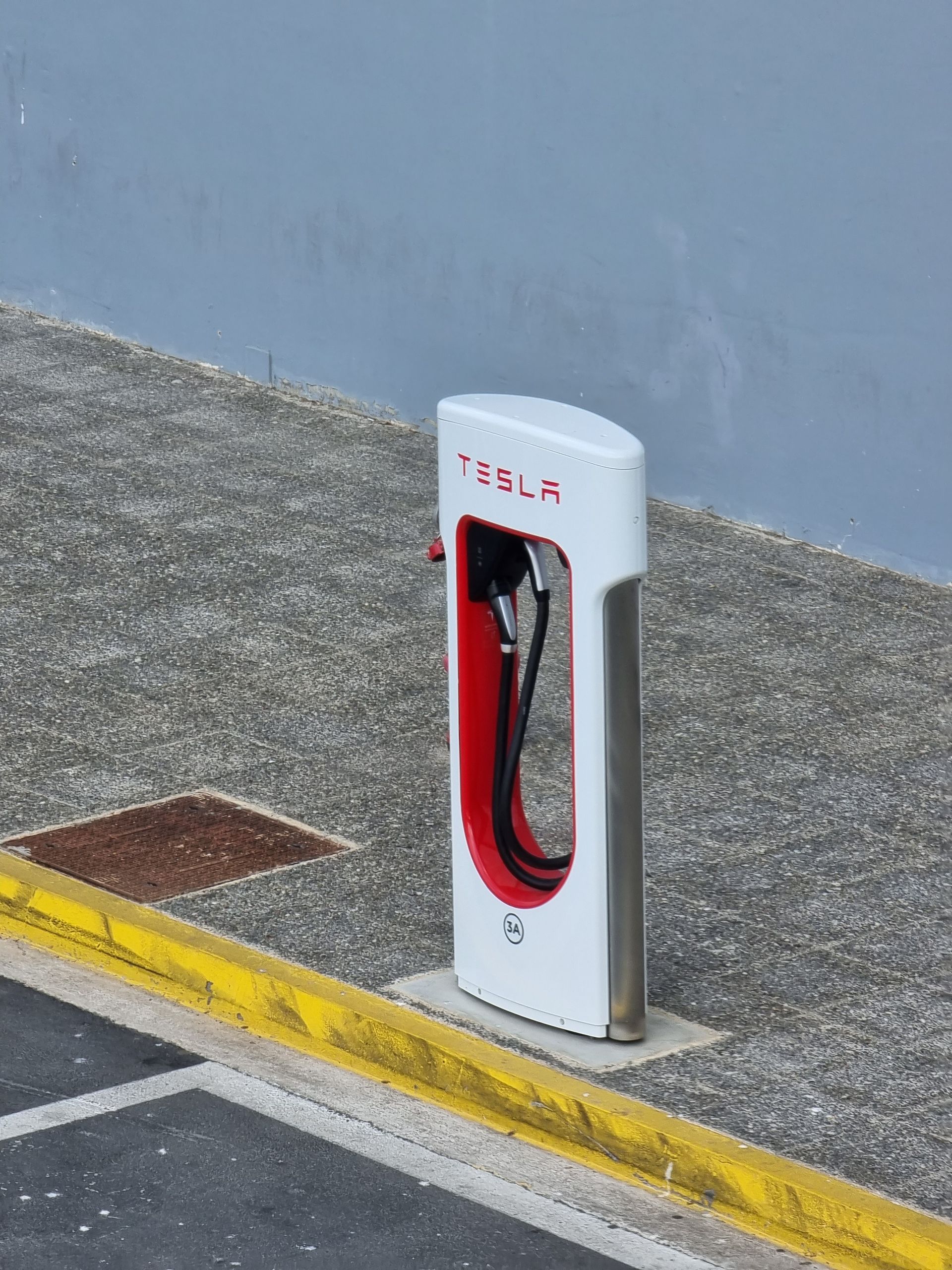 Can the Volvo EX30 Use Tesla Superchargers? Tesla Supercharger station on a city sidewalk, ideal for promoting electric vehicle infrastructure.