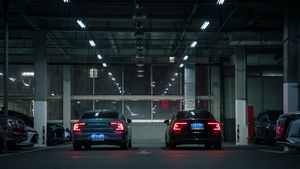 Two modern cars in an urban indoor parking garage during night time, showcasing sleek automotive design.