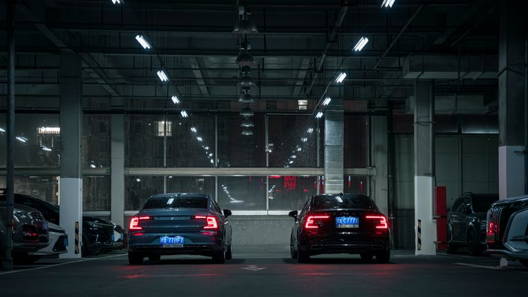 Two modern cars in an urban indoor parking garage during night time, showcasing sleek automotive design.