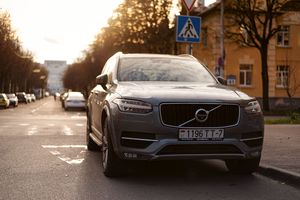 A Volvo XC90 parked on an urban street in Minsk during sunset with urban surroundings.